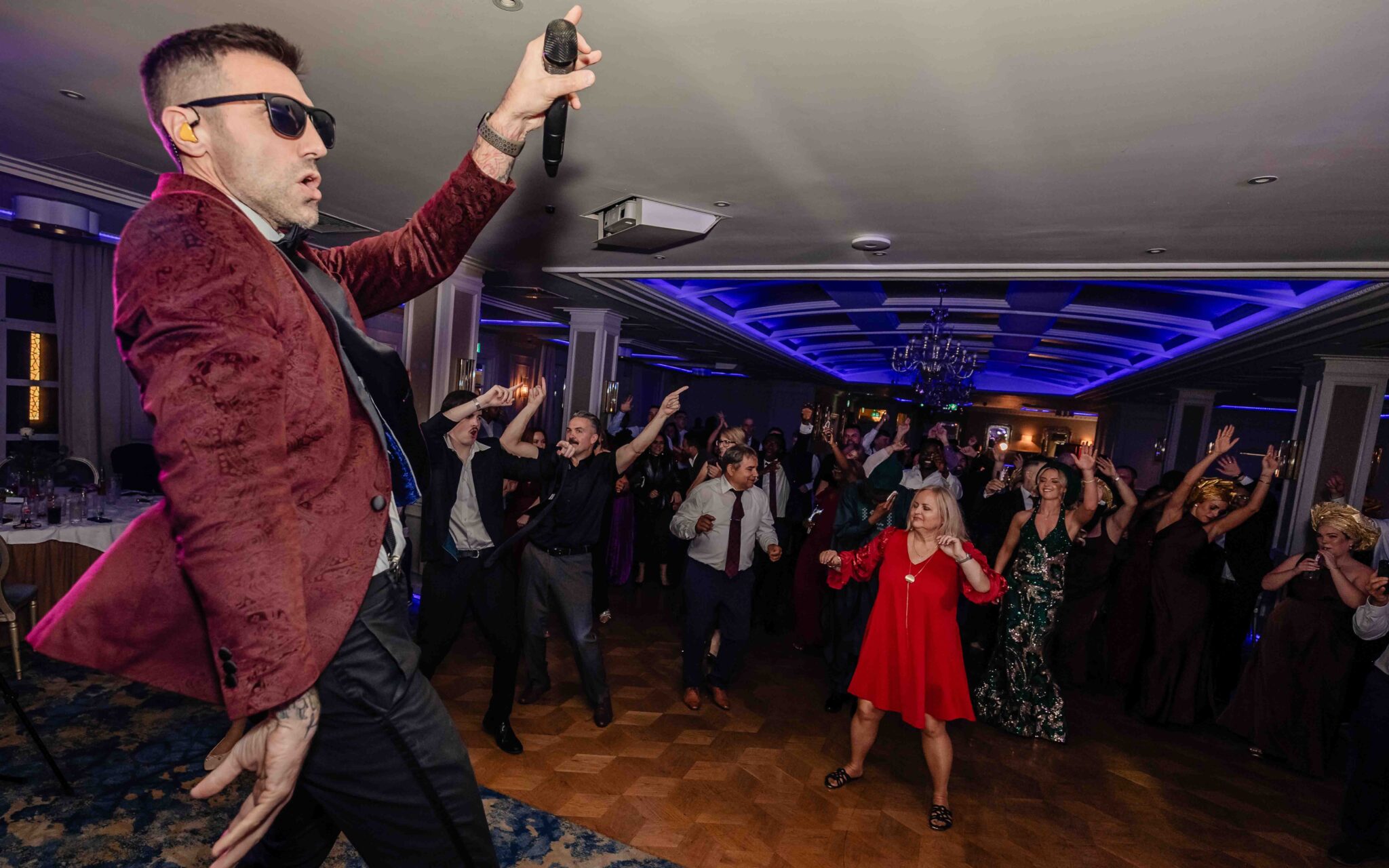 Wedding band performer in sunglasses and a red jacket entertains the full ballroom at Vienna Woods Hotel, Cork
