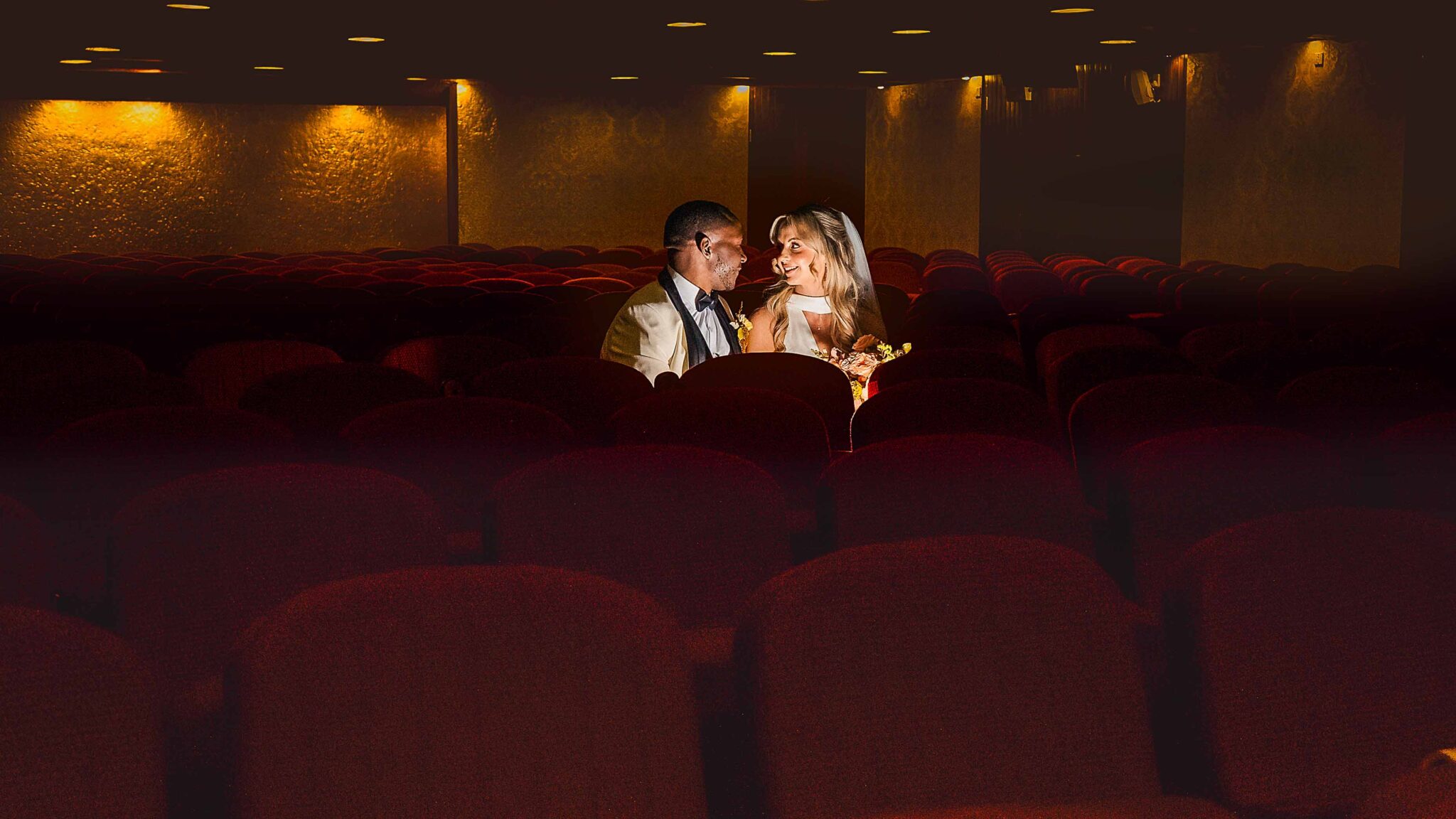 Bride and groom share a quiet moment among red seats at Cork Church, Oliver Plunkett Street, Cork wedding photographer
