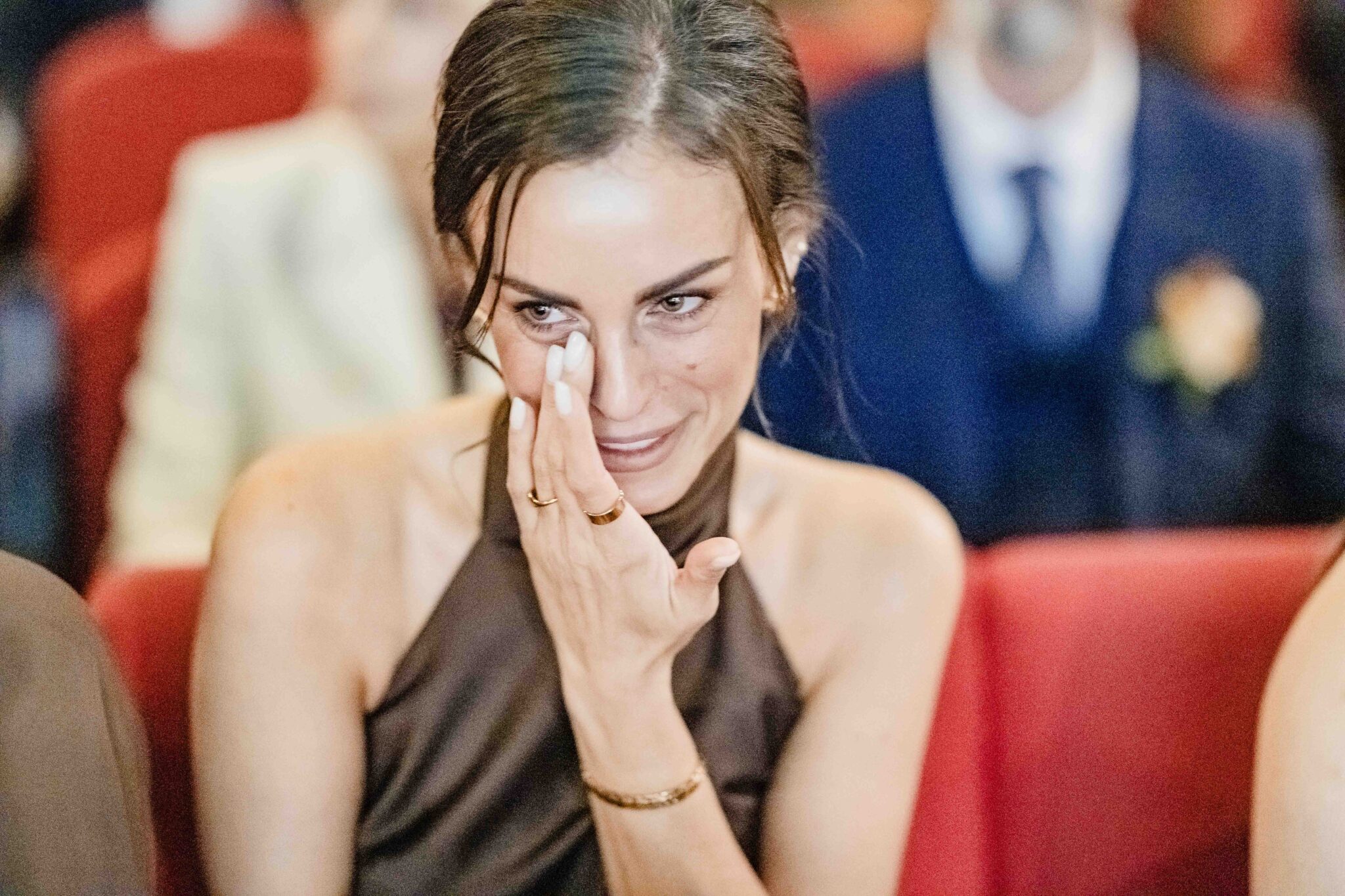 Bridesmaid in brown satin wipes away a tear during the ceremony at Cork Church, emotional wedding photography Cork