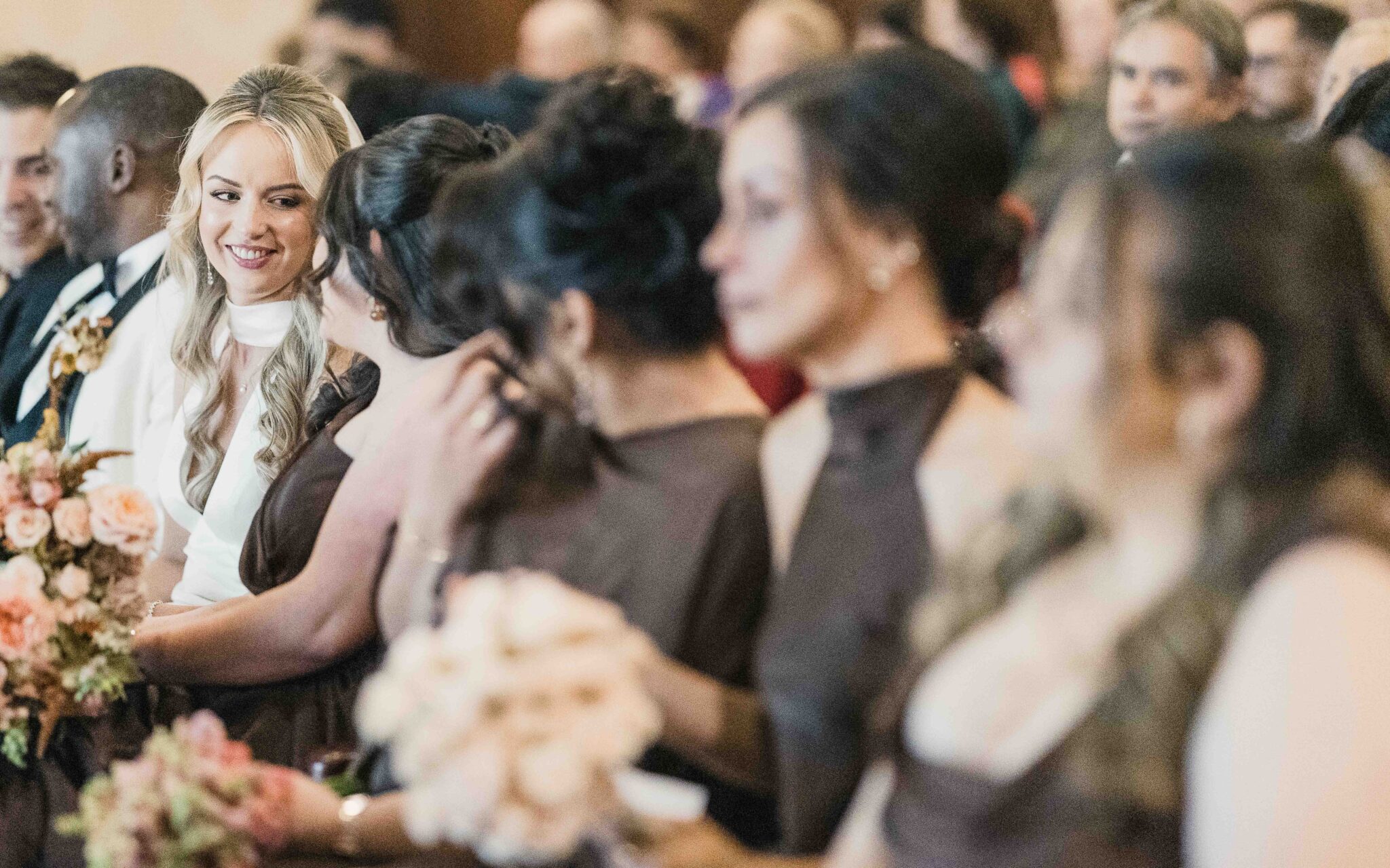 Bridesmaids in chocolate brown satin hold peach and orange bouquets during the ceremony at Cork Church