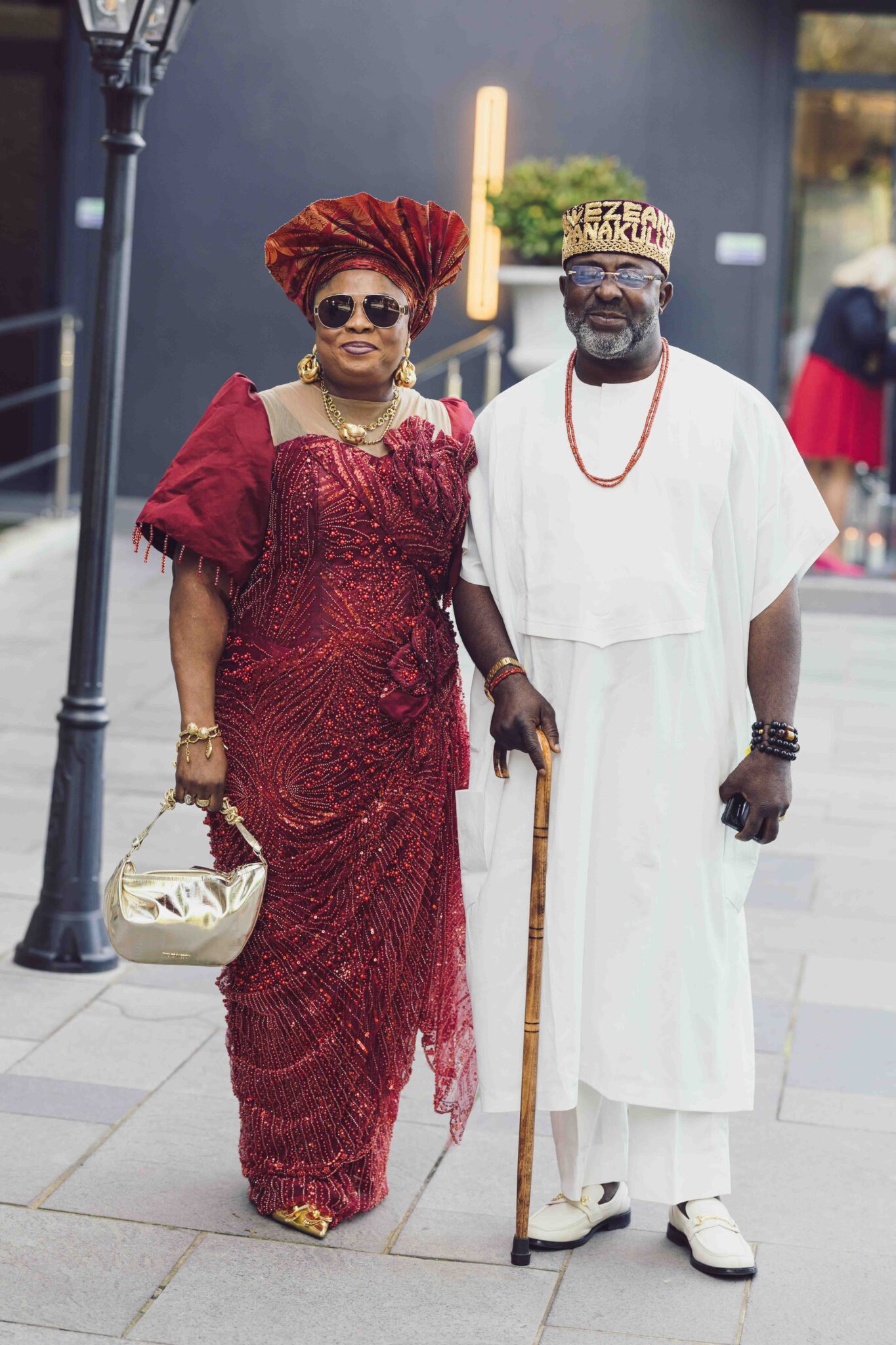 Wedding guests in traditional Nigerian dress, a woman in red and a man in white with a cane, Irish Nigerian wedding Cork
