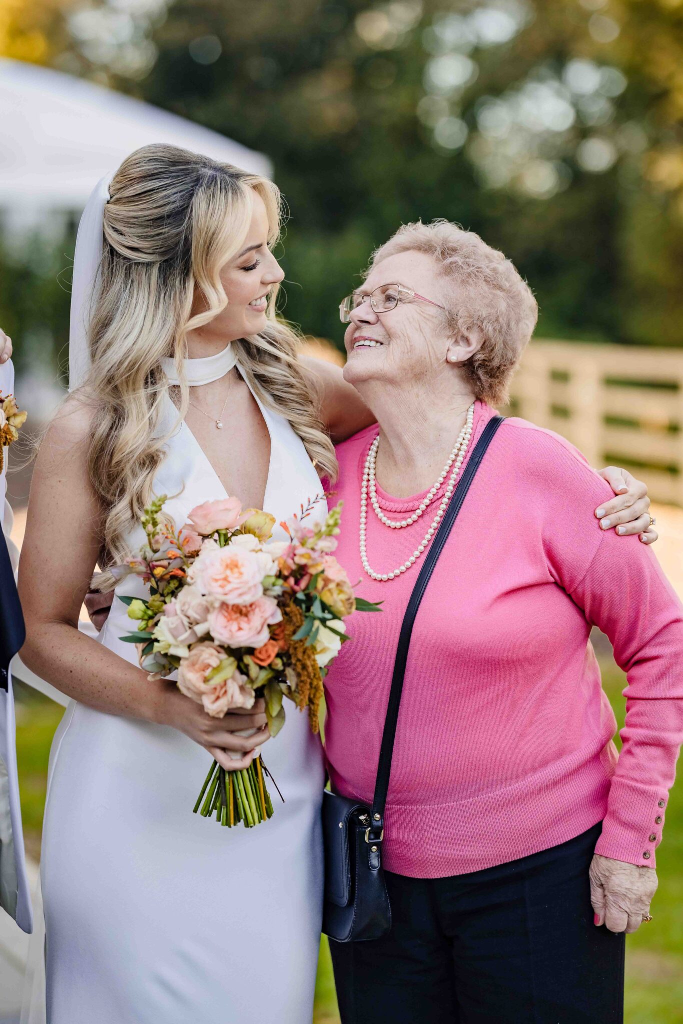 Stacey laughs with an older guest in a pink cardigan in the gardens at Vienna Woods Hotel wedding, Cork