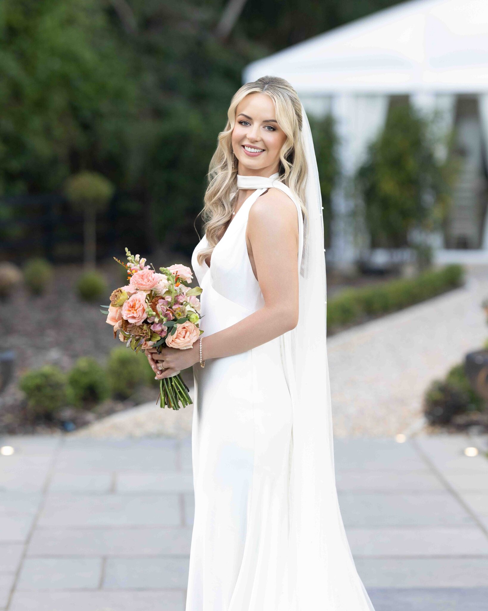 Bride holds a peach and orange bouquet on the stone path at Vienna Woods Hotel, Cork bridal portrait