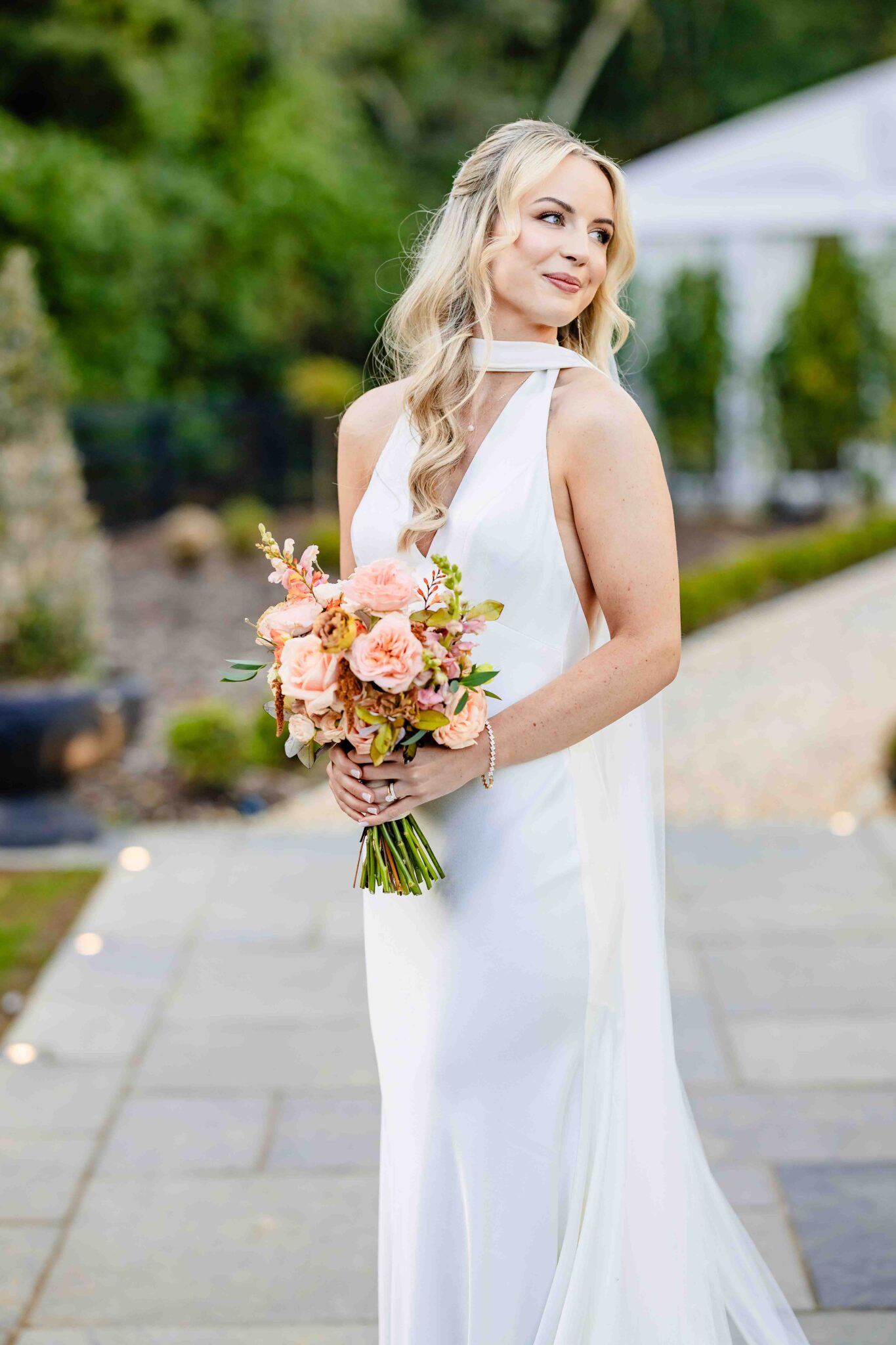 Bride looks over her shoulder holding her bouquet on the garden path at Vienna Woods Hotel, Cork bride