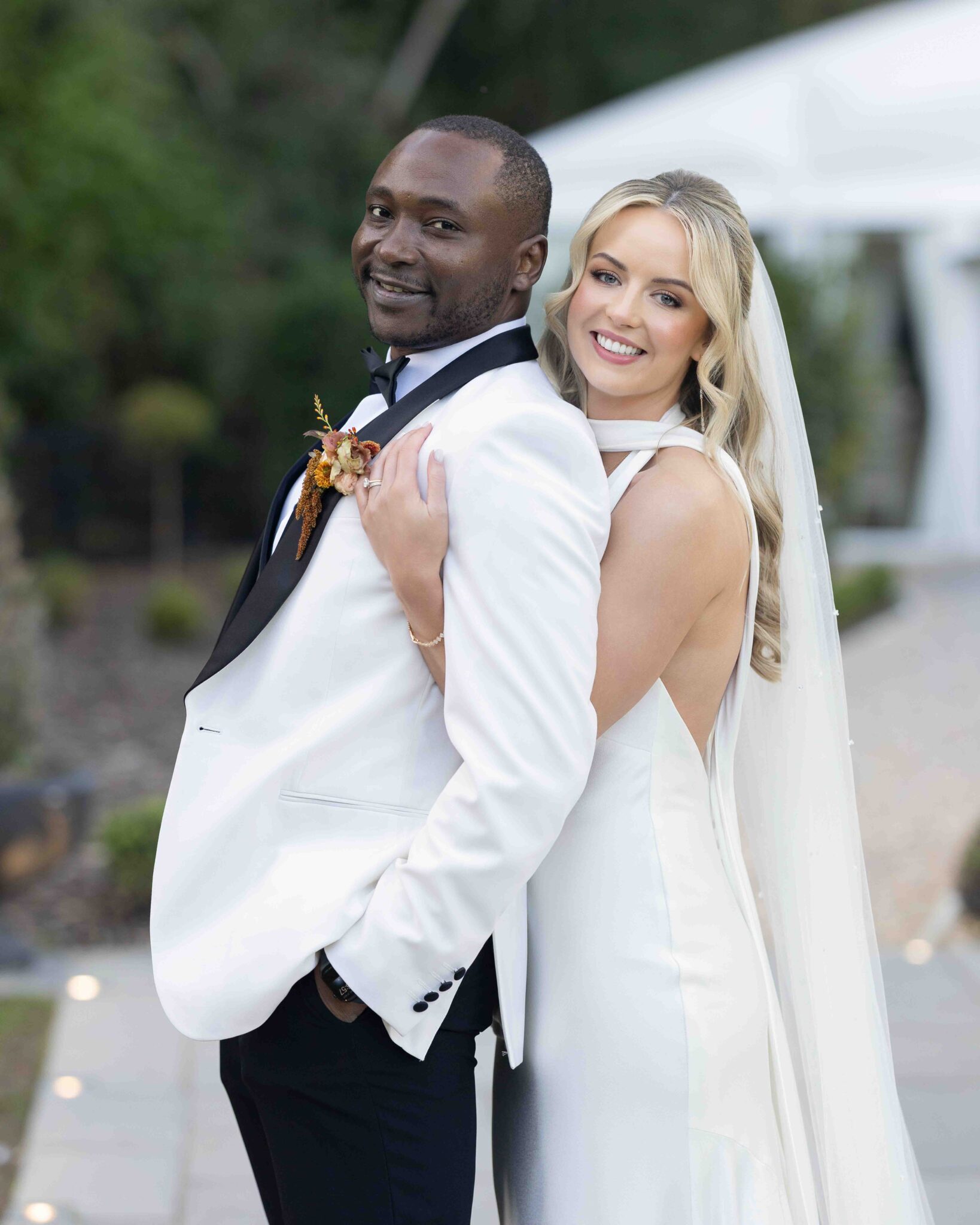 Groom hugs Stacey from behind in the autumn gardens at Vienna Woods Hotel, romantic wedding photography Cork