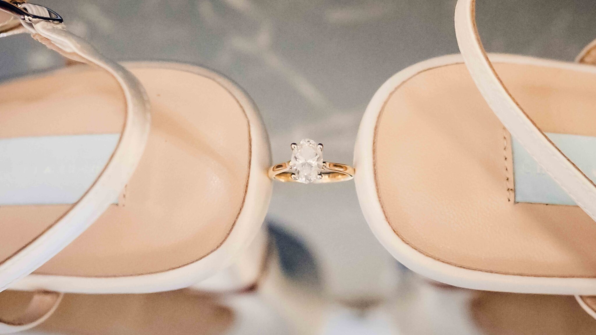 Wedding rings resting between the bride's white satin wedding shoes, wedding detail photography Cork
