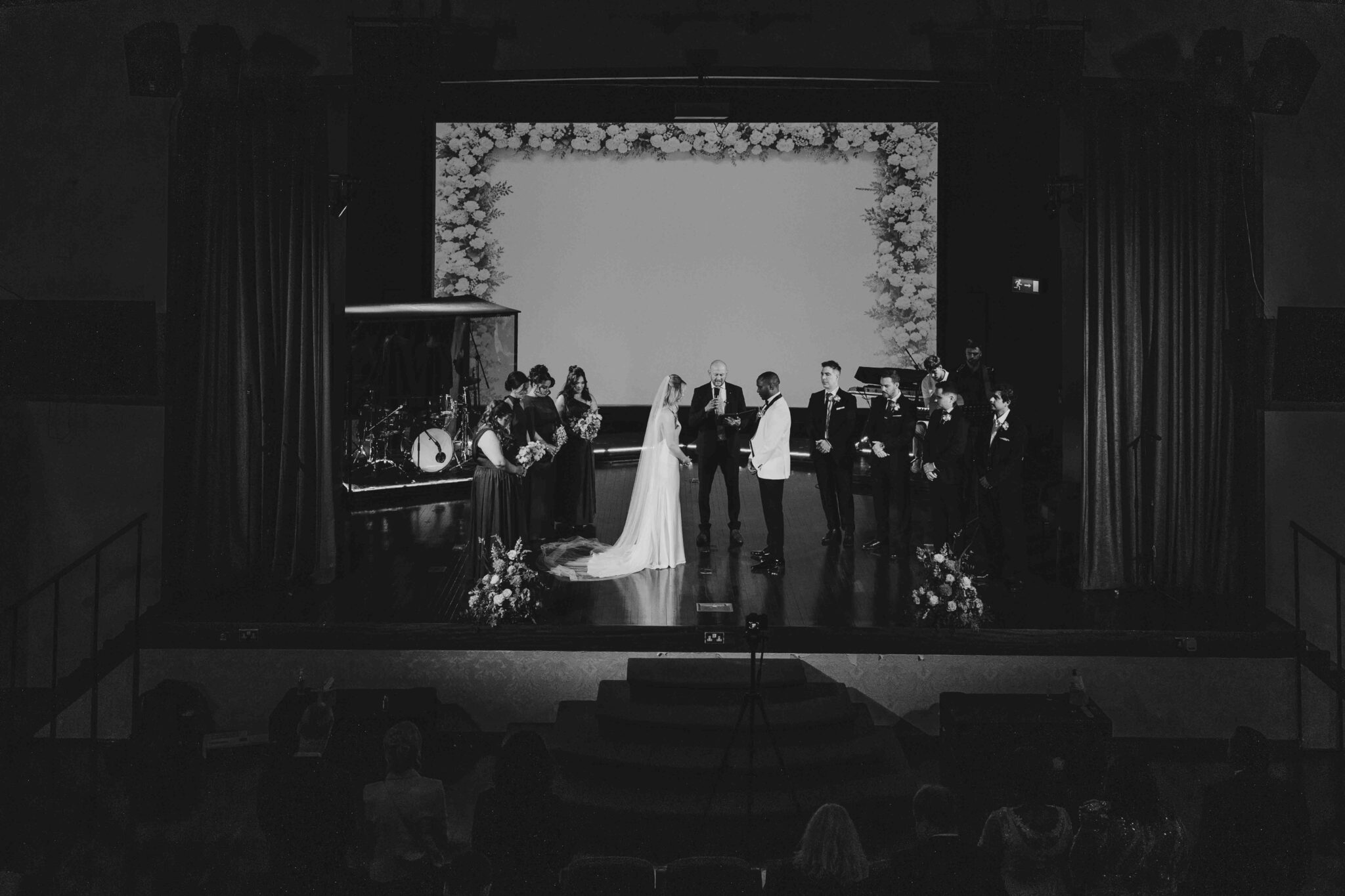 Black and white wide shot of the wedding ceremony on the stage at Cork Church, Cork wedding photographer