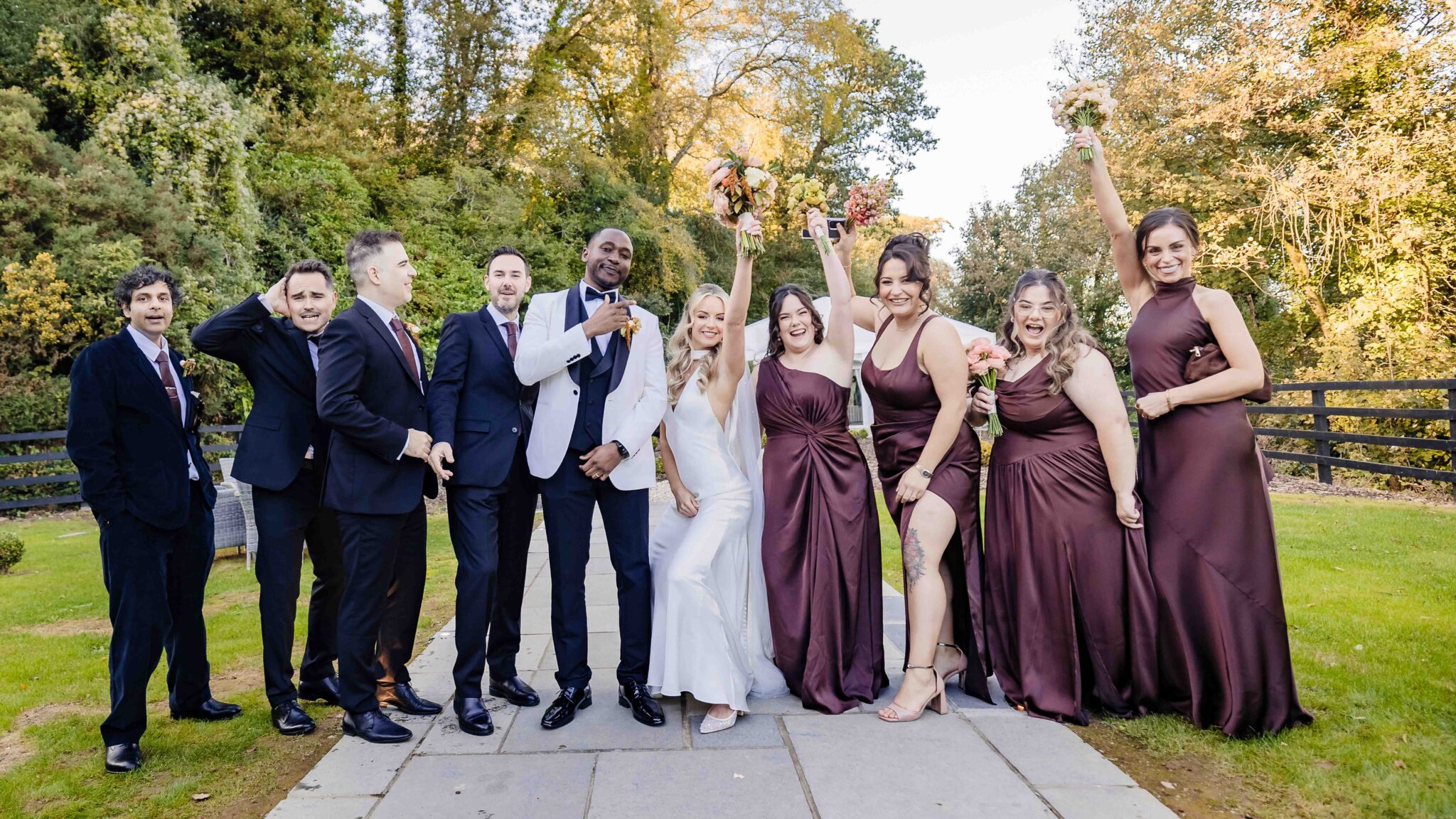 Groomsmen and bridesmaids celebrate with the bride and groom on the lawn at Vienna Woods Hotel, Cork wedding party
