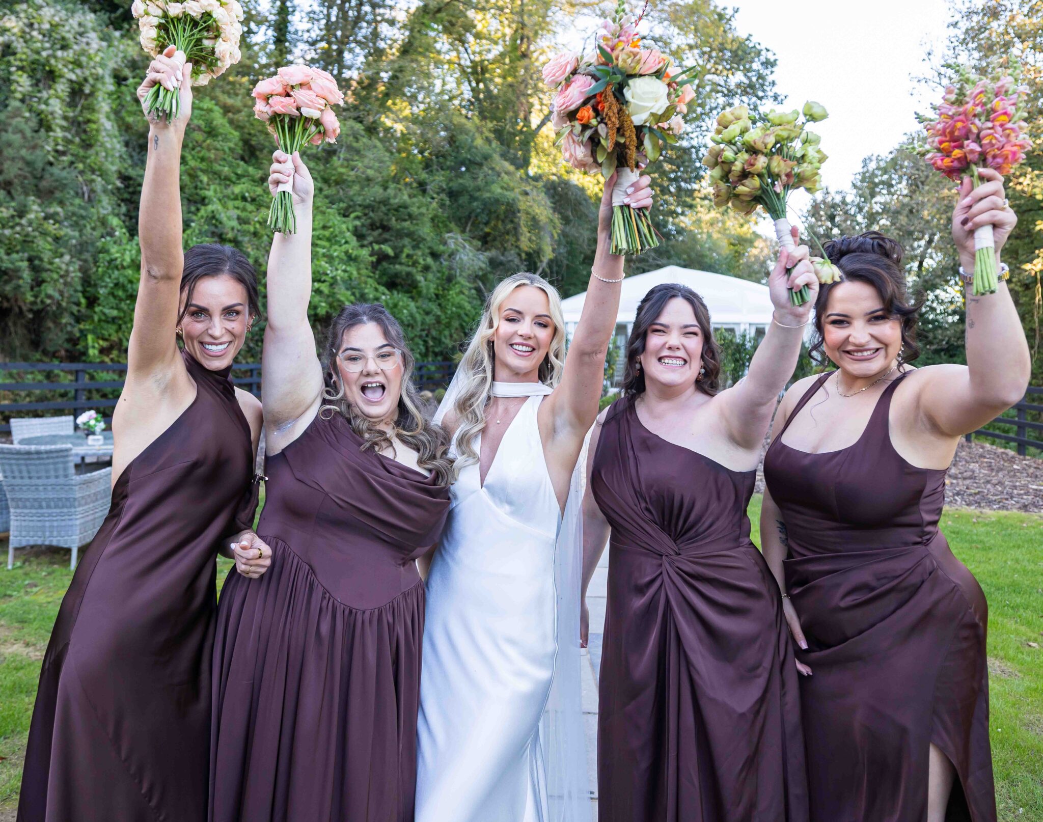 Bridesmaids and bride raise their bouquets in celebration at Vienna Woods Hotel, wedding photographers Cork