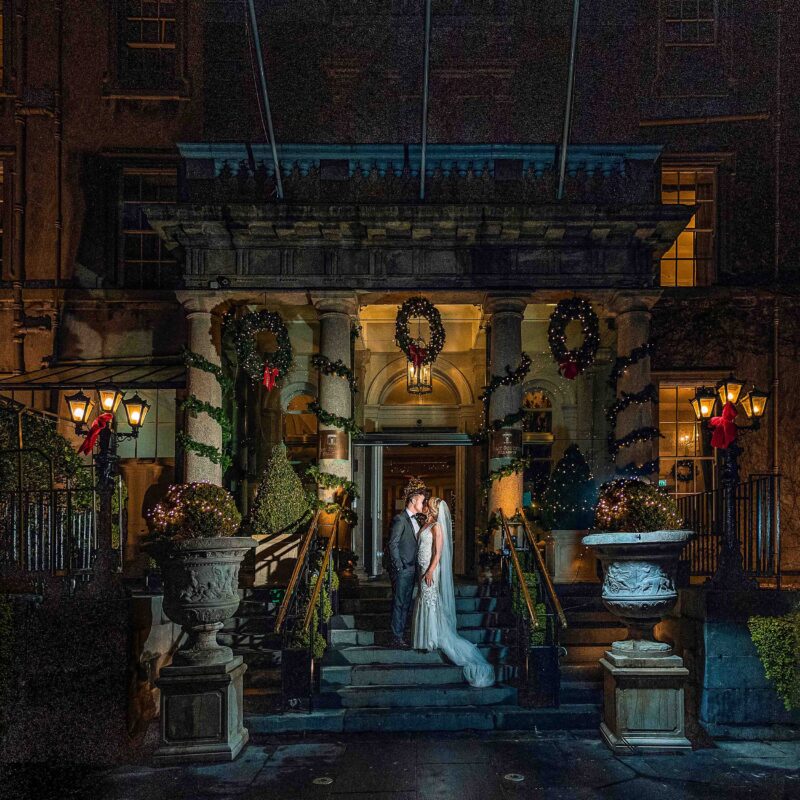 Bride and groom sharing a kiss at Christmas Outside the Great Southern Hotel in Killarney